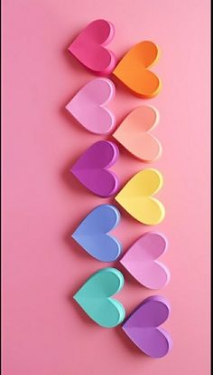 colorful paper hearts arranged on a pink background