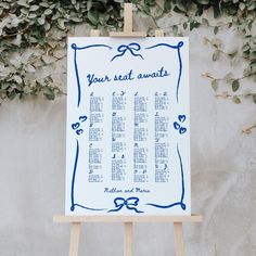 a wedding seating chart on an easel in front of a wall