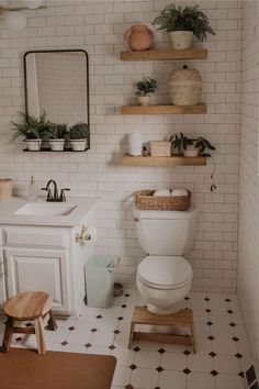 a white toilet sitting in a bathroom next to a sink and a wooden shelf filled with potted plants