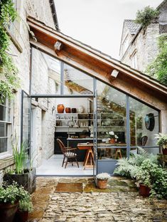 an outdoor kitchen and dining area in a stone walled building with glass doors that open up to the outside patio