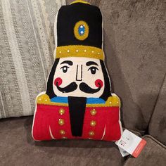 a pillow with a nutcracker on it is sitting on a couch next to a tag