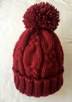 a red knitted hat with a pom - pom on top