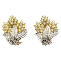 These super sparkly diamond cluster earrings absolutely glow. The elegant two toned design pops beautifully on the lobe, giving a chic and glamorous look. These beautiful earrings each feature shimmering clusters of white and fancy light yellow diamonds in a half flame motif. The bottom half of the pair are filled with natural white pave diamonds (H-I / SI) set in polished 14 karat white gold 'flames'. The white gold setting brightens up the icy white stones and makes them really pop. Above the flames sit a cluster of fancy light yellow diamonds set in polished 14 karat yellow gold, enhancing the subtle warmth of the natural stones and making them glow. A post and lever-back closure hugs the lobe for a secure fit. These earrings are in very good estate condition and have been professionall Luxury Yellow Gold Brilliant Cut Cluster Earrings, Luxury Yellow Gold Festive Danglers, White Cluster Diamond Earrings For Formal Occasions, White Diamond Cluster Earrings For Formal Events, White Diamond Cluster Earrings For Formal Occasions, Anniversary White Diamond Clip-on Earrings, White Diamond Clip-on Earrings, White Cluster Diamond Earrings With Accents, White Cluster Diamond Earrings With Diamond Accents