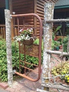 an old iron gate with flowers growing in the basket on it's front porch