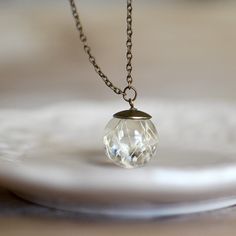 This delicate handcrafted resin sphere holds a cluster of a beautiful Gypsophila, better known as "Baby's Breath". Hand-cast and hand-polished to luster, pendant measures approximately 2 cm in diameter and comes to wear on the 18 inches long chain. Very delicate and dainty, this necklace is perfect for the wedding, elegant outfit or just every day!Please make your choice of a bronze or silver tone chain.Note: flowers in nature do not look exactly alike, so there will be some slight variations in Delicate Round Crystal Necklace For Gift, Delicate Round Crystal Necklaces For Gift, Spiritual Glass Jewelry With Round Pendant, Spiritual Orb-shaped Jewelry Gift, Spiritual Round Glass Pendant Jewelry, Spiritual Glass Pendant Jewelry, Handmade Elegant Spherical Jewelry, Elegant Round Glass Crystal Necklaces, Delicate Round Hypoallergenic Necklace