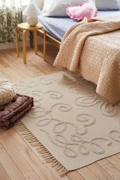 a bed room with a neatly made bed and a rug on the floor next to it