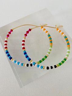 Colorful glass rainbow beads adorn a gold hoop earring. These lightweight earrings are so versatile. Cheap Multicolor Beaded Earrings For Beach, Trendy Beaded Earrings, Rainbow Bead Earrings, Colorful Beaded Hoop Earrings For Everyday Summer, Multicolor Vibrant Jewelry With Ear Wire, Summer Rainbow Jewelry With Dangling Beads, Vibrant Multicolor Jewelry With Ear Wire, Vibrant Multicolor Earrings, Multicolor Hoop Earrings With Ear Wire