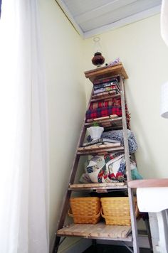 an old ladder is used as a shelf in the corner of a room with baskets on it