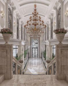 an ornate hallway with chandelier and marble pillars in the center is flanked by two large planters