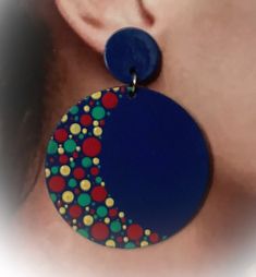 a close up of a person's ear wearing earrings with circles and dots on them