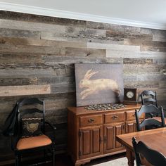 a dining room with wood paneling and chairs in front of a painting on the wall