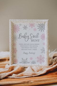 a baby sock hunt sign sitting on top of a wooden table next to a blanket