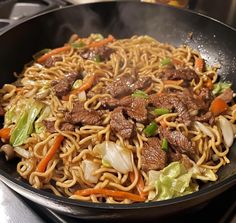 a wok filled with beef and noodles on top of a stove