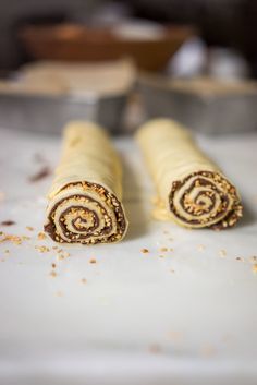 two rolled up food items sitting on top of a white tablecloth covered in brown and yellow sprinkles