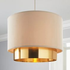 a light fixture with a beige shade hanging from it's ceiling in a living room