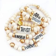 Affirmation bracelets featuring a hand painted lettered focal bead by Audra and off white beads and gold logo charm. Stretchy to fit most wrists. For a custom word/phrase more than 6 letters, please email info@audrastyle.com with your request. For custom words/phrases less than 6 letters, please choose the Custom option and leave the request in the notes at checkout. Handmade Meaningful White Beaded Bracelets, Handmade White Beaded Bracelets With Meaningful Style, Inspirational White Name Bracelet With Round Beads, White Wooden Beads Stretch Bracelet As Gift, White Stretch Bracelet With Wooden Beads For Gift, White Inspirational Stretch Bracelet With 8mm Beads, Inspirational White Bracelet With 8mm Beads, Inspirational Handmade White Stretch Bracelet, Inspirational White Stretch Bracelet