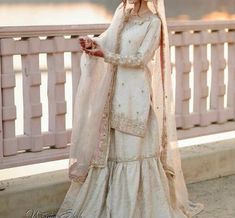 a woman in a wedding dress standing on a bridge