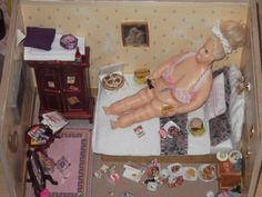 there is a doll laying on a bed in a toy house with other toys around it