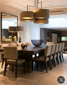 a large dining room table with chairs and lamps on it's sides, in front of an open floor plan