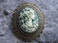 You choose silver or gold plated. Beautifully hand painted cameo pendant necklaces, individually painted and antiqued by me, so each is an original. They are offered at a reasonable price, make perfect gifts, and are wonderful quality. The cameo is set in a stunning silver or gold plated setting, please see the photos for size. I can make any of my Victorian woman cameos into this pretty piece, so please do browse and message me with your custom order. I make several varieties, colors, styles an Collectible Cameo Pendant Brooches, Victorian Baroque Brooches As Gifts, Victorian Handmade Pendant Brooches, Ornate Bronze Brooch Jewelry, Artistic Formal Brooch Jewelry, Handmade Victorian Brooches As Gifts, Handmade Victorian Brooches For Gift, Ornate Antique Gold Brooches For Collectors, Antique Green Cameo Jewelry