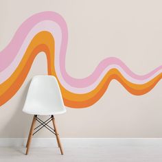 a white chair sitting in front of a wall with an orange and pink wave painted on it