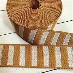 a roll of orange and white striped ribbon on a wooden floor next to a pair of scissors