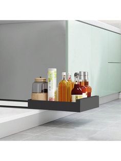 a shelf with bottles and spices in it on the counter top next to a sink