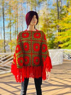 a mannequin wearing a red and green crocheted ponchy cape