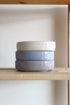 three bowls sitting on top of a wooden shelf