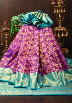 This purple Kanjivaram pure silk saree is a masterpiece of traditional craftsmanship and opulent design. The rich purple hue exudes regal elegance, while the exquisite floral zari brocade adds a layer of intricate, shimmering detail that enhances the saree's luxurious appeal. The saree is framed by striking blue contrast borders, which provide a vibrant and complementary touch to the overall design. The combination of the deep purple, intricate zari work, and bold blue borders makes this saree a stunning choice for grand occasions, ensuring you make a memorable and sophisticated statement. SILK MARK CERTIFIED This saree is ready to wear with fall and pico done. Handmade silk tassels adorn the pallu and add more grace to it. An unstitched blouse fabric is included. *Note: There may be minor Regal Elegance, Silk Tassels, Saree Blouses, Pure Silk Saree, Rich Purple, Zari Work, Purple Hues, Pure Silk Sarees, Blouse Fabric