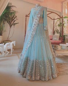 a blue and silver lehenga is on display in a room with white furniture