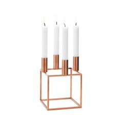 three candles are placed in a metal holder with four white candles on each candleholder