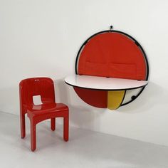 a red chair next to a white table with a black and yellow design on it