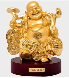 a golden buddha statue sitting on top of a wooden base with gold decorations around it