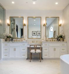 a large bathroom with two sinks, mirrors and a tub in the middle of it