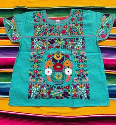 "Gorgeous! Mexican colorful blouses !! Each blouse has UNIQUE - colorful embroidery, each blouse has unique color of hem neck ., please check pictures. When shipping I will choose at random any blouse depending on the color fabric or size choose from buyer unless buyer request a picture of blouse before check out. Fabric: cotton- manta - ( great quality) fresh fabric. Care : hand wash or dry cleaning only. Please check measurements before purchase. Read my shipping policy as well. MEASUREMENTS A Traditional Green Shirt For Spring, Blue Cotton Tops With Motif, Blue Motif Tops For Festivals, Traditional Green Embroidered Tops, Blue Tops With Motifs For Festivals, Traditional Blue Tops With Motif, Traditional Green Tops With Floral Embroidery, Traditional Multicolor Summer Shirt, Traditional Shirt With Multicolor Embroidery For Summer