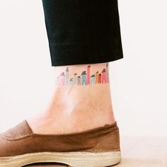 a person with a small city tattoo on their ankle