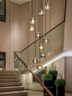 an elegant staircase with glass balls hanging from the ceiling and potted plants on the steps