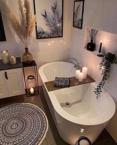 a white bath tub sitting in a bathroom next to a rug and two candles on top of it