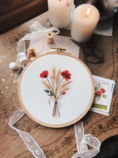 an embroidery project with flowers and candles on a table