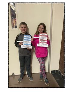 two young children standing next to each other holding up some papers with writing on them