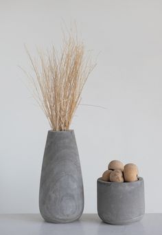 two gray vases sitting next to each other on top of a white countertop