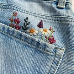 a pair of jeans with embroidered flowers in the back pocket