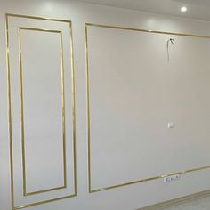 an empty room with white walls and gold trim