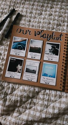 an open notebook sitting on top of a bed next to pens and paper with pictures