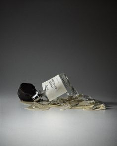 a glass bottle filled with liquid sitting on top of a pile of broken glass shards