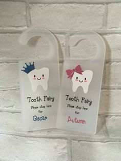 two plastic toothbrush holders hanging on a brick wall with the words tooth fairy and tooth fairy printed on them