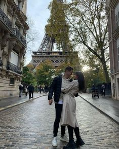 a man and woman standing in front of the eiffel tower