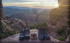 two pairs of hiking shoes sitting on top of a cliff overlooking the valley and mountains