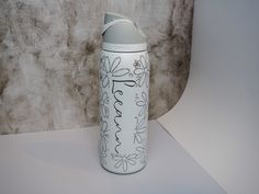 a white and black water bottle sitting on top of a table next to a wall